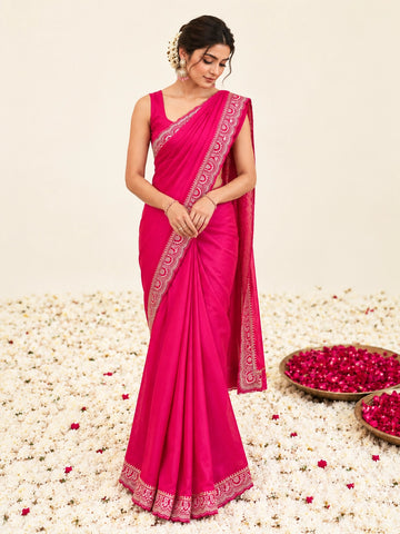 Woman in a vibrant RANI  saree with gold border, sitting among white flowers.