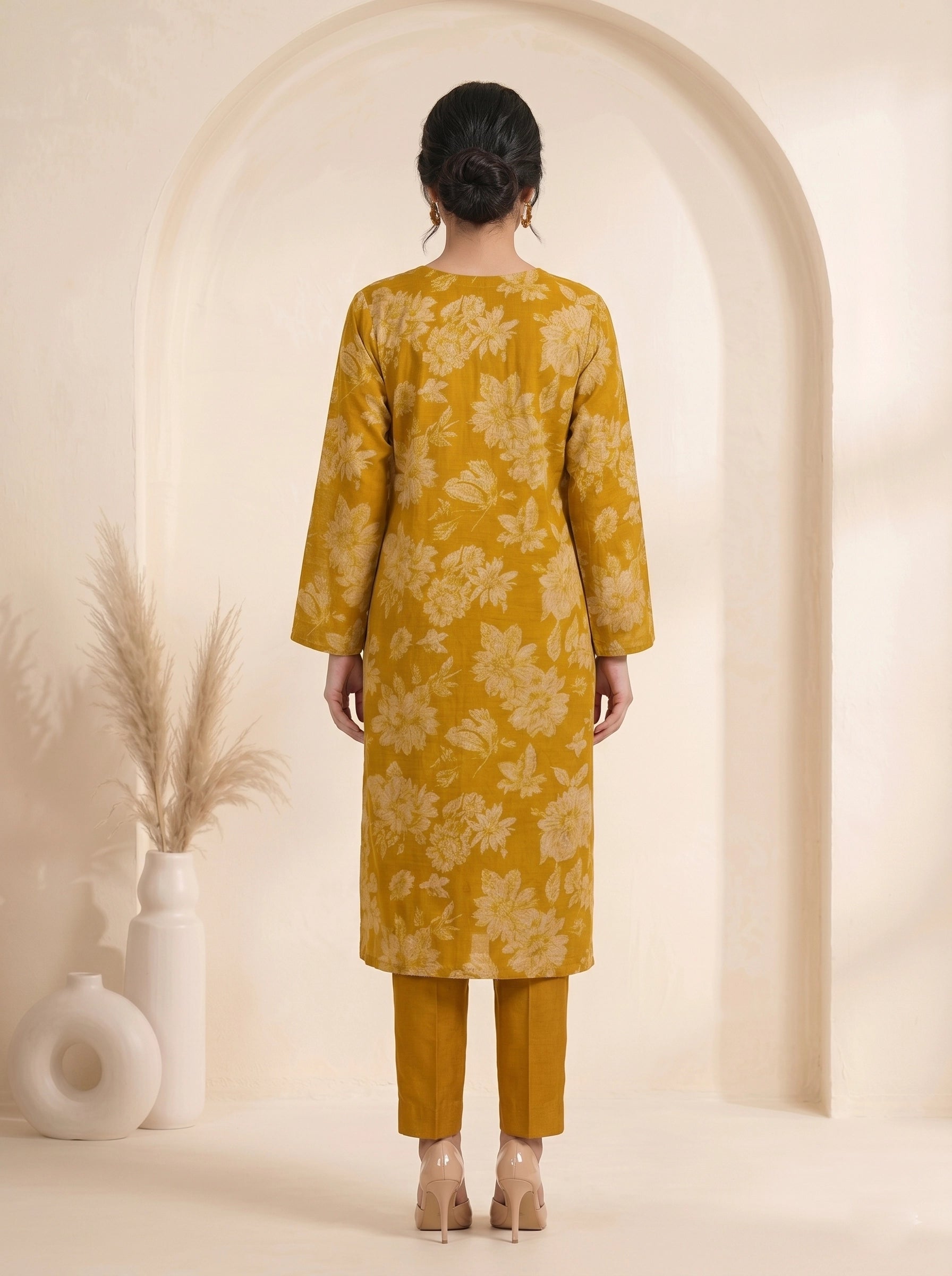 Woman wearing a mustard yellow floral print cotton kurti set with a dupatta and beige heels.