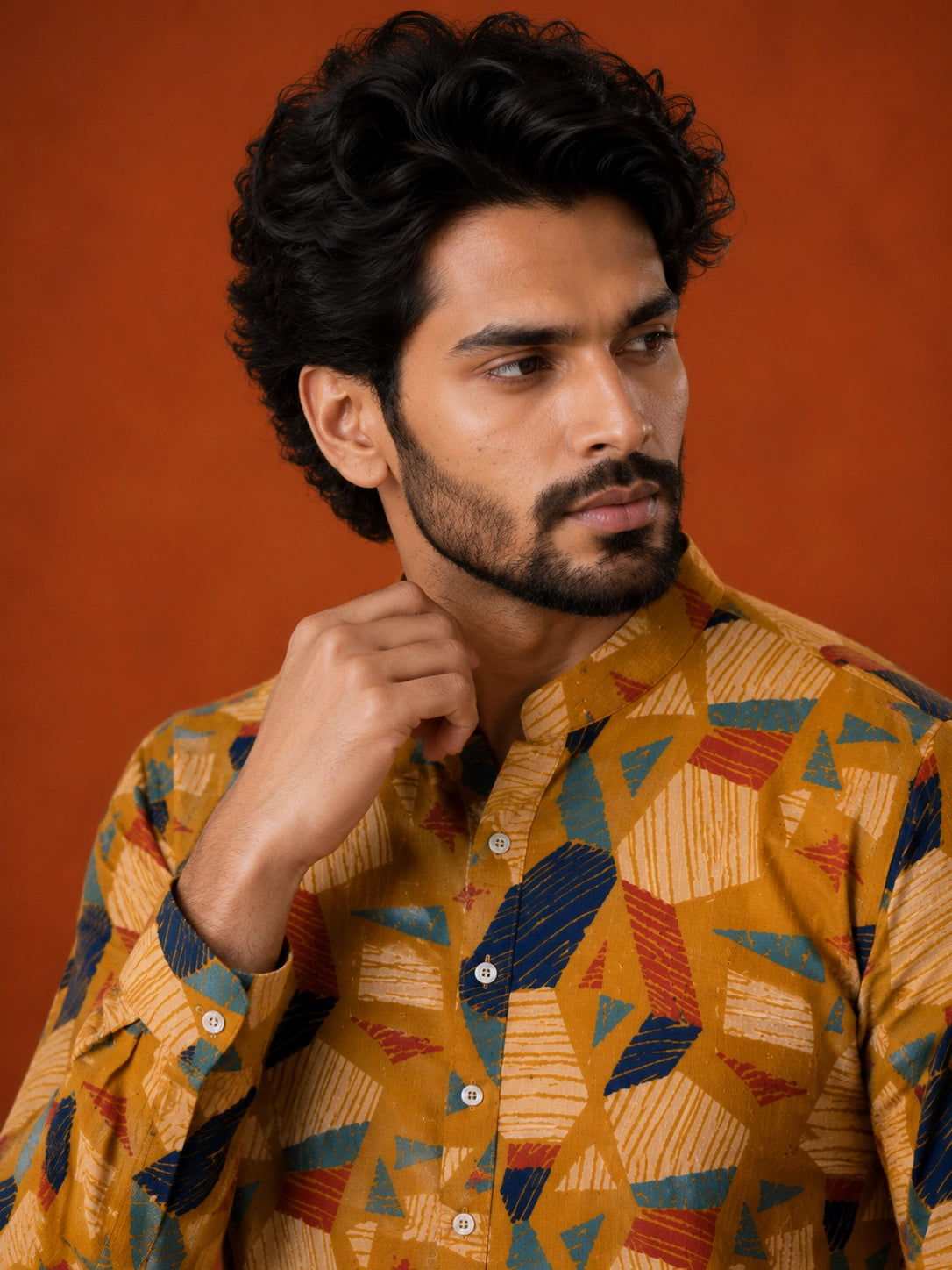 Man wearing a mustard kurta with blue, red, and white geometric print and white pajama.