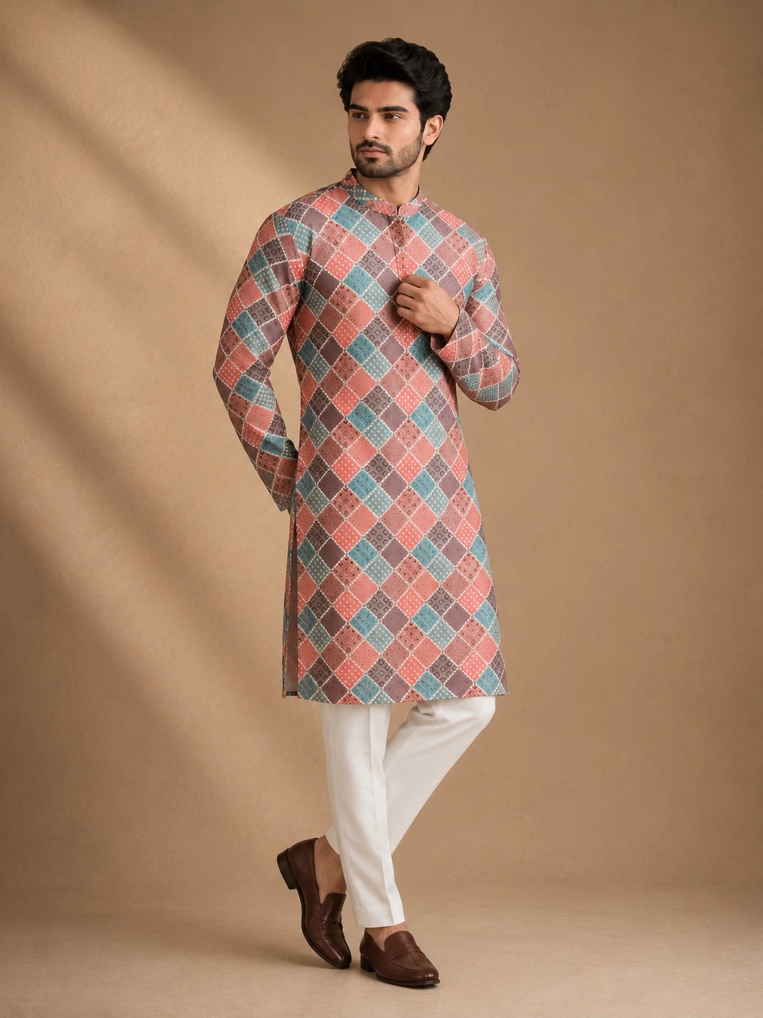 Man in a vibrant geometric diamond print kurta, white pajama, and brown loafers.