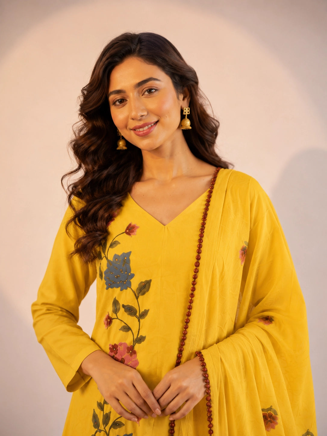 Woman in a vibrant yellow kurti set with colorful floral embroidery and dupatta.