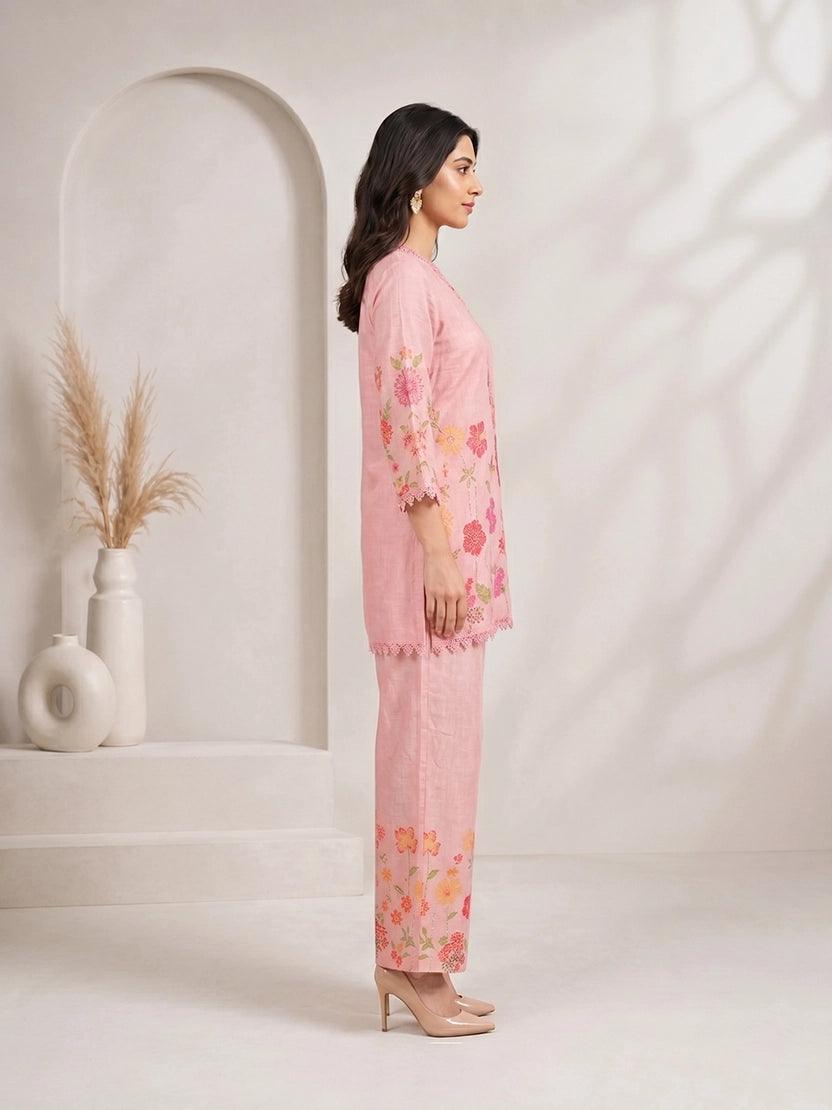 Woman wearing a pink floral print kurta with matching palazzo pants and lace trim.