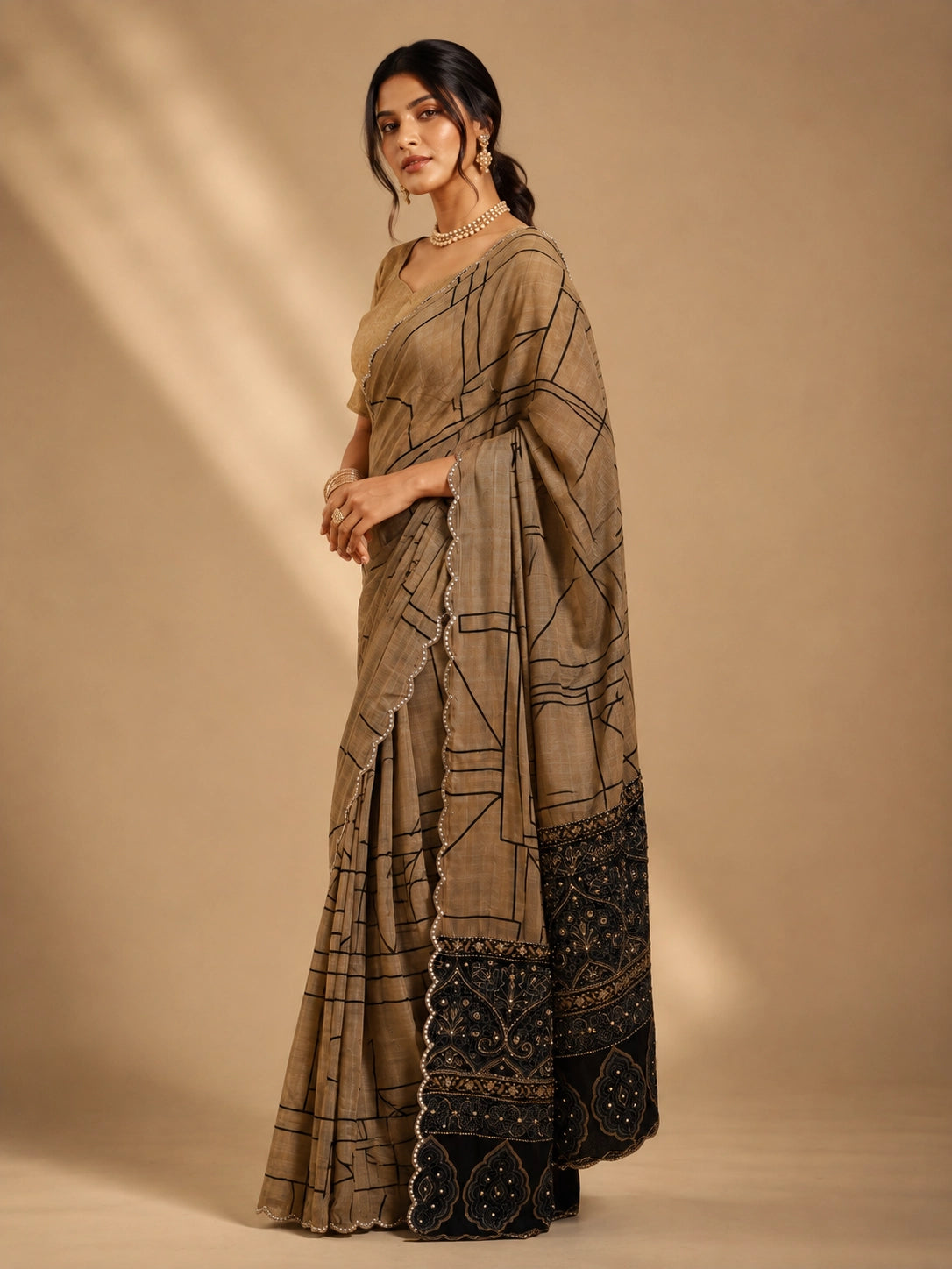 Woman in elegant brown  saree with black geometric print and embellished border.