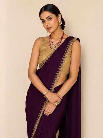 Woman in elegant wine saree with golden embroidered border and matching blouse