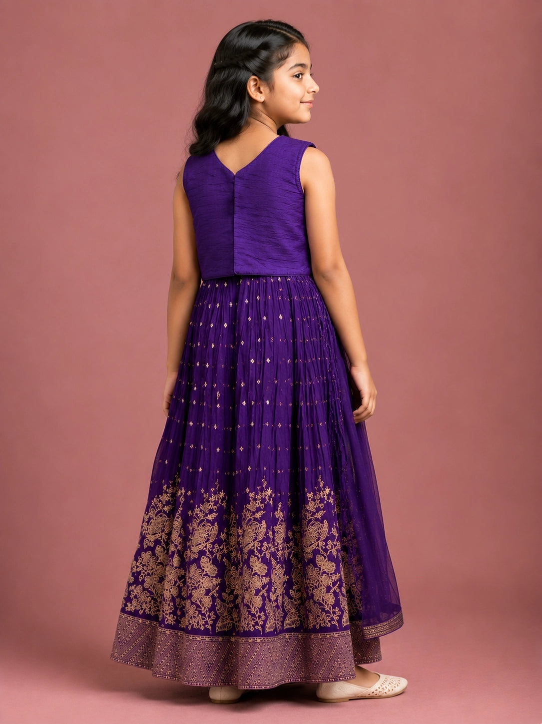 Young girl wearing a vibrant purple lehenga choli with intricate gold embroidery.