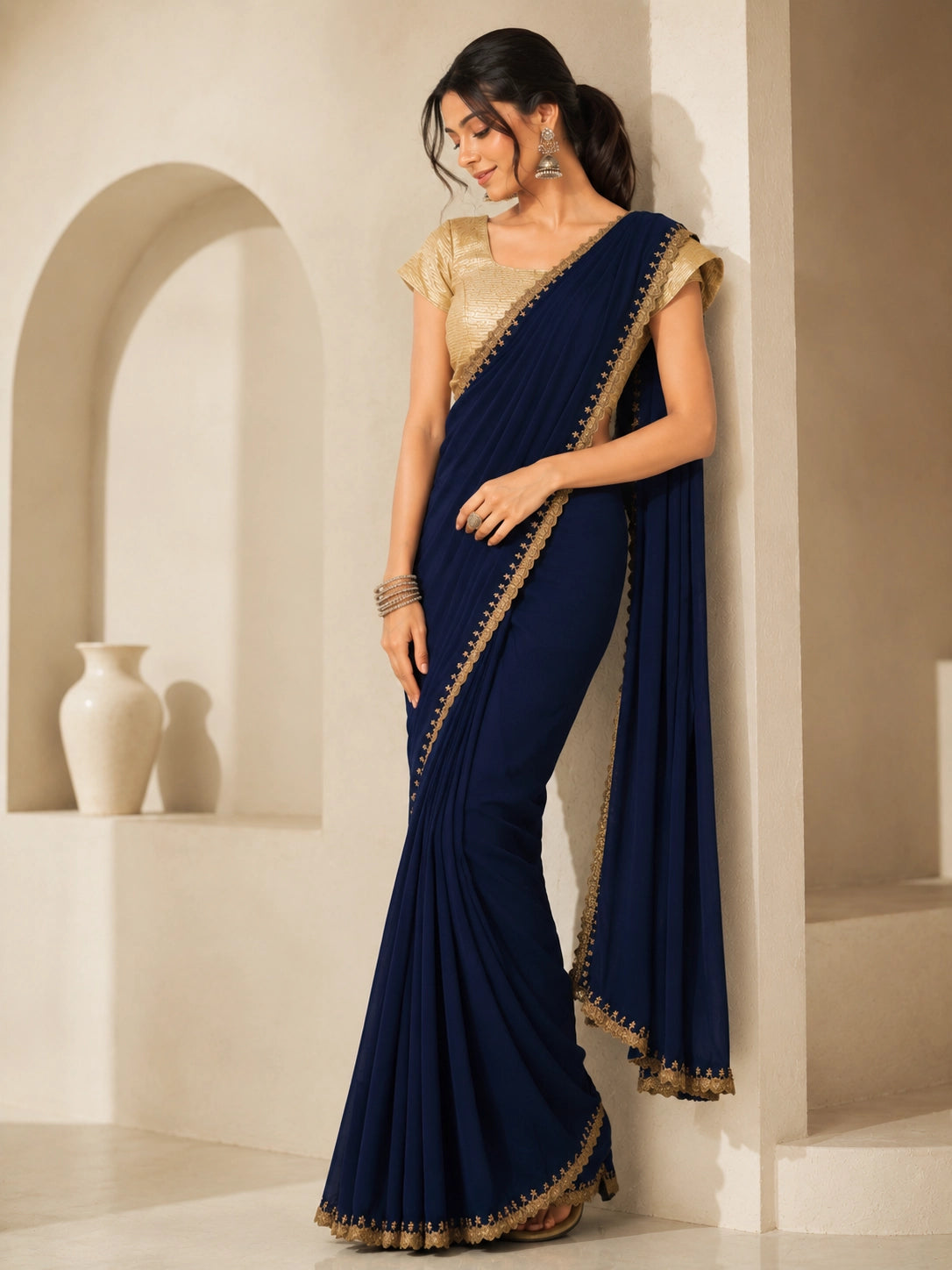 Woman wearing a navy blue saree with gold embroidered borders and a gold blouse.