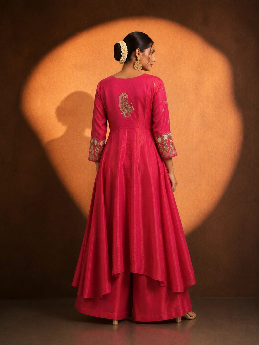 Woman in a vibrant rani pink embroidered kurti set with a flowing silhouette.