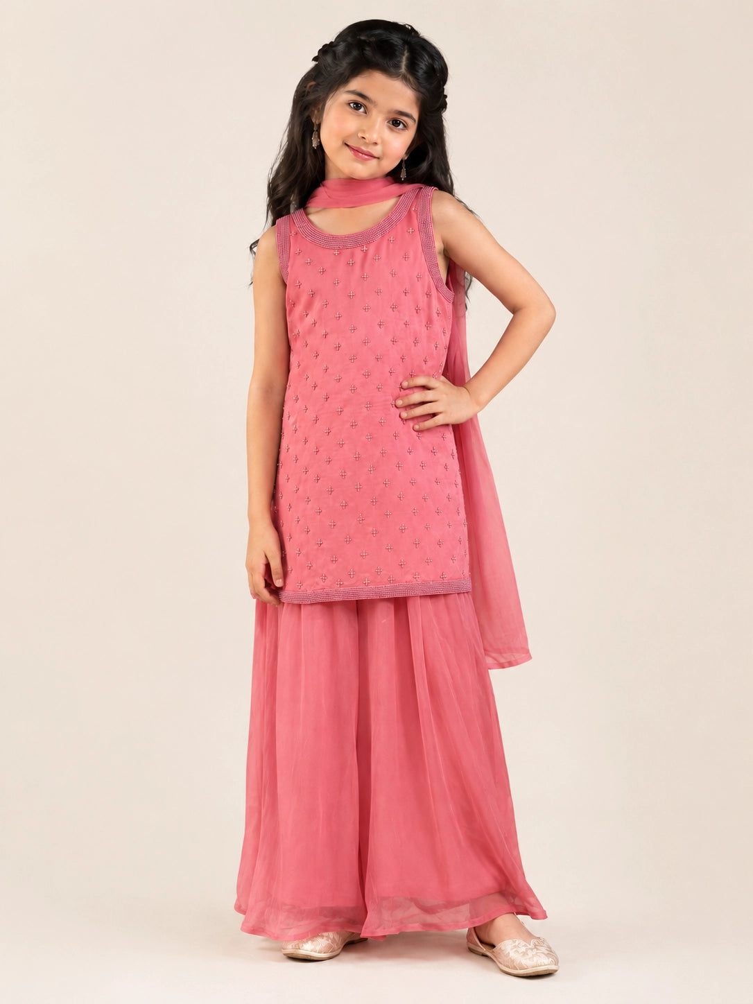 Young girl in a pink sleeveless kurta with beaded embroidery and flowy pink sharara pants.
