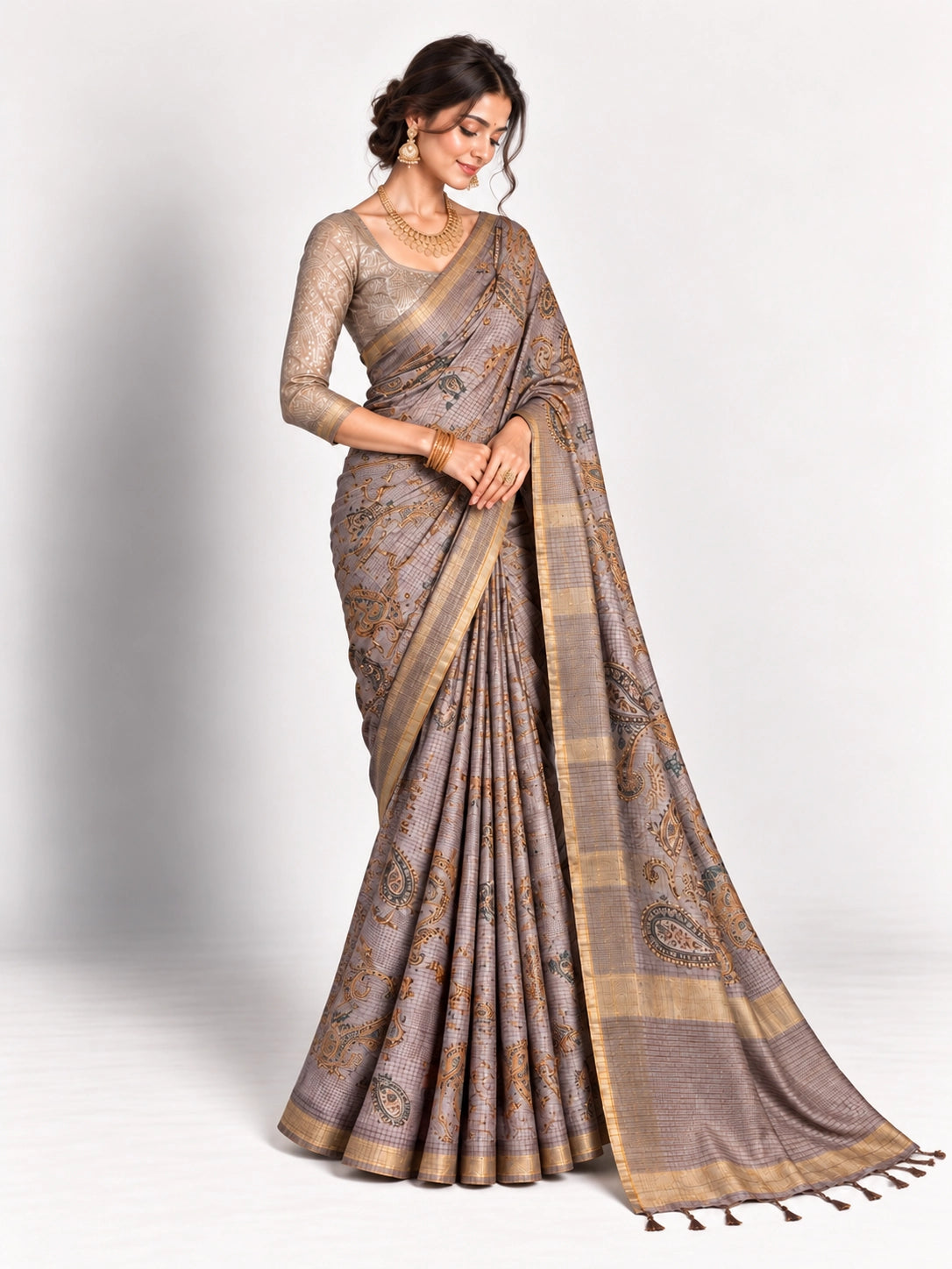 Woman in an elegant lavender grey saree with gold border and intricate paisley patterns.