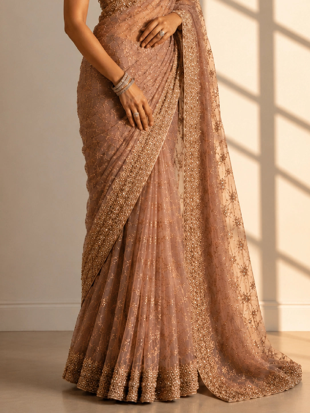 Woman in an elegant pink S3 embellished saree with intricate gold work and sleeveless blouse.