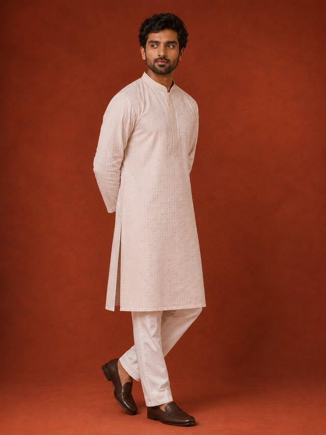 Man in elegant white kurta pajama with subtle vertical and diamond patterns.