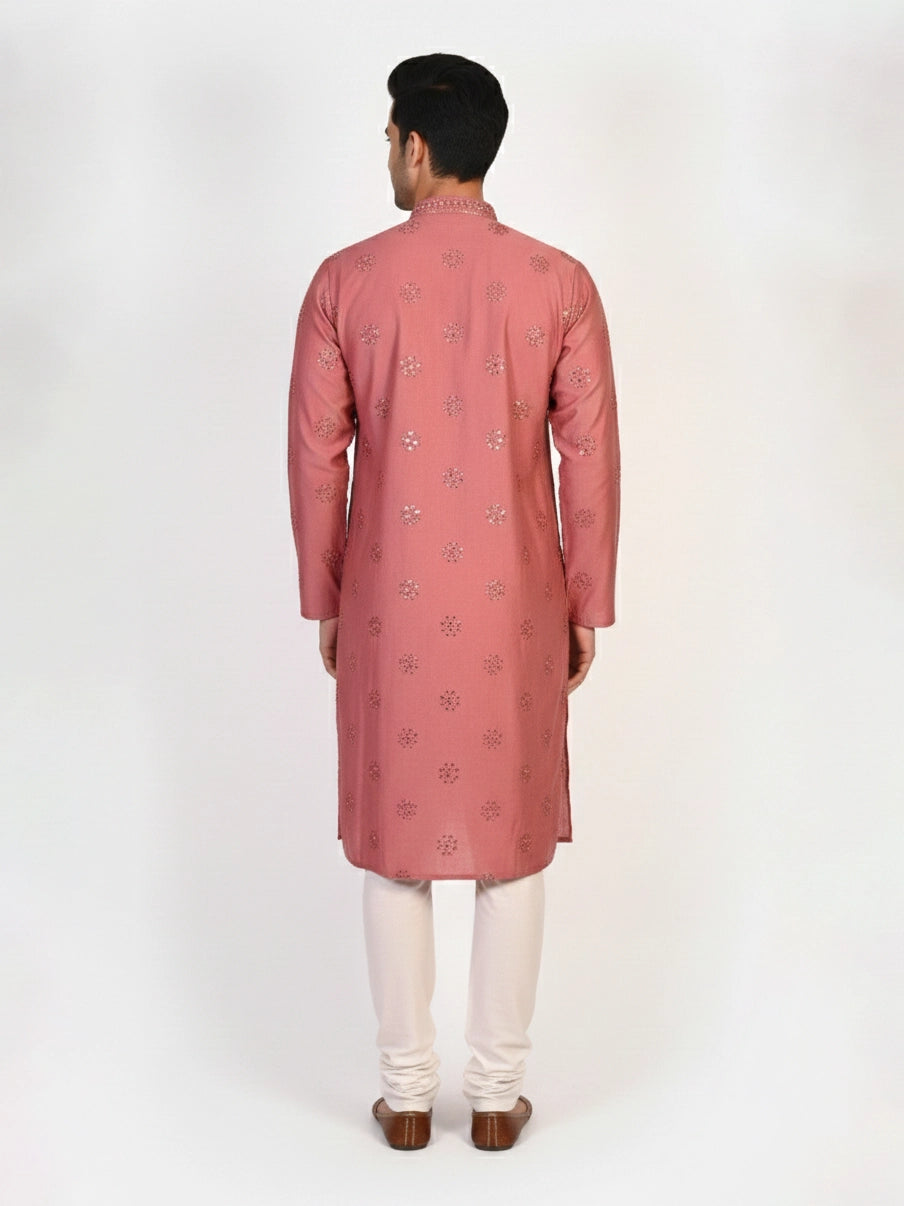 Man wearing a rose embroidered Kurta Pajama with white pants and brown jutti shoes.