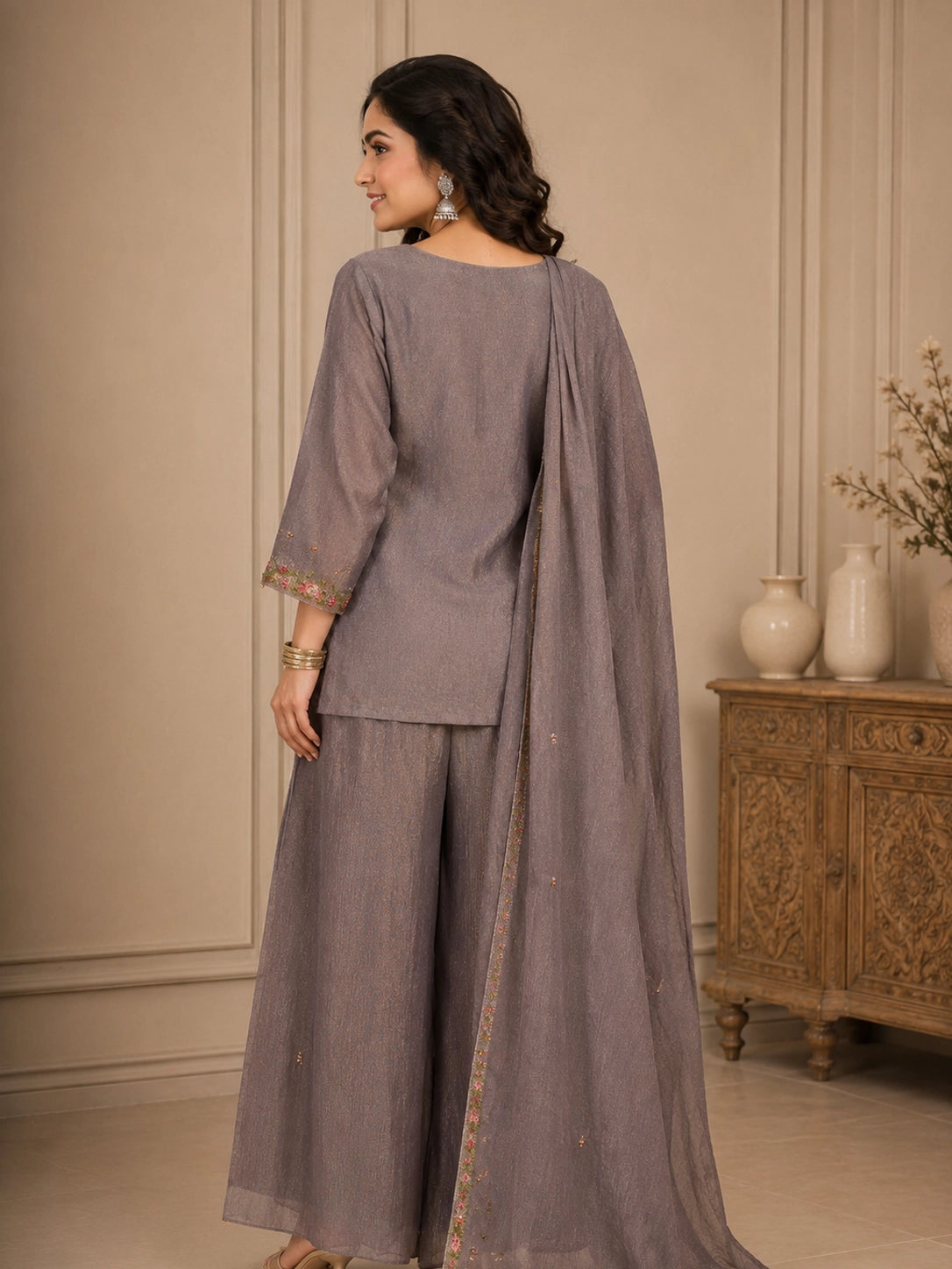 Woman wearing a pink embroidered choker neck Sharara with floral details on sleeves and hem.