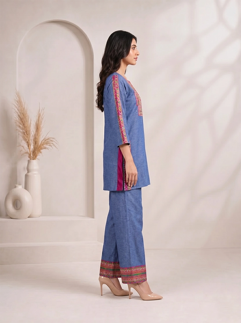 Woman wearing a blue embroidered kurta and matching wide-leg pants with a geometric border, styled with nude heels.