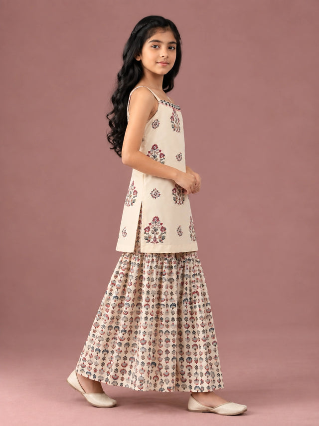 Young girl in a cream floral print strappy top and matching flared sharara set.
