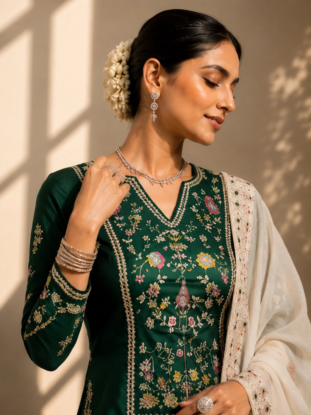 Elegant woman in a dark green embroidered kurta, cream pleated skirt, and matching dupatta.
