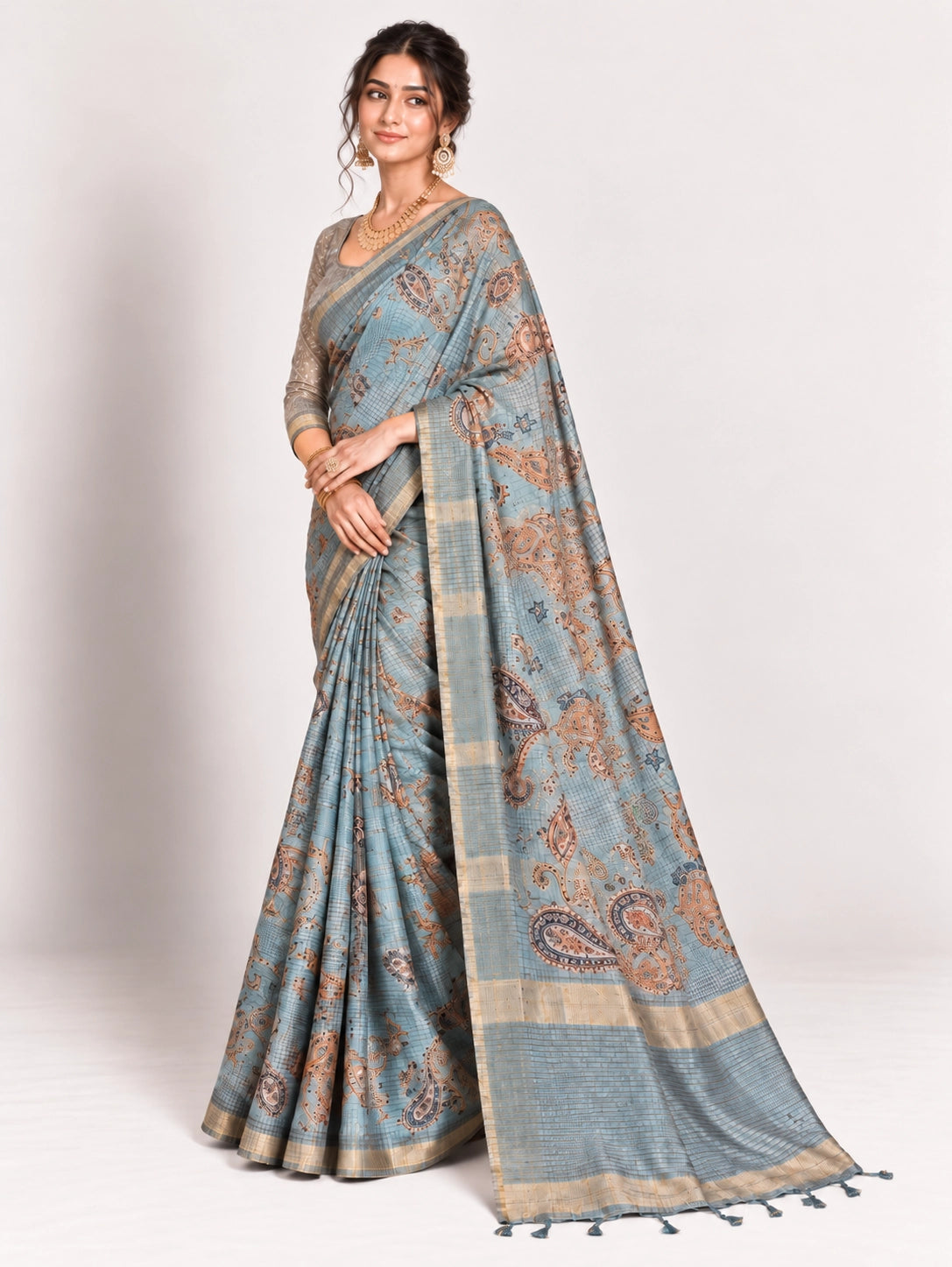 Woman in an elegant lavender grey saree with gold border and intricate paisley patterns.