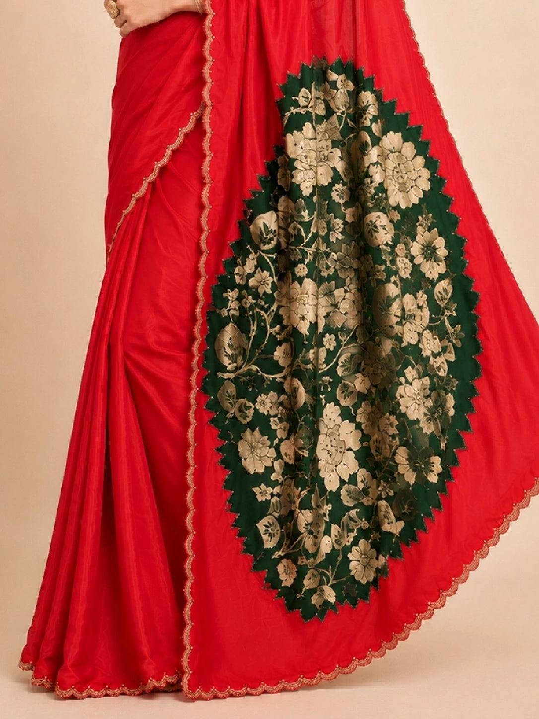 Woman wearing a vibrant red saree with a gold scalloped border and traditional jewelry.