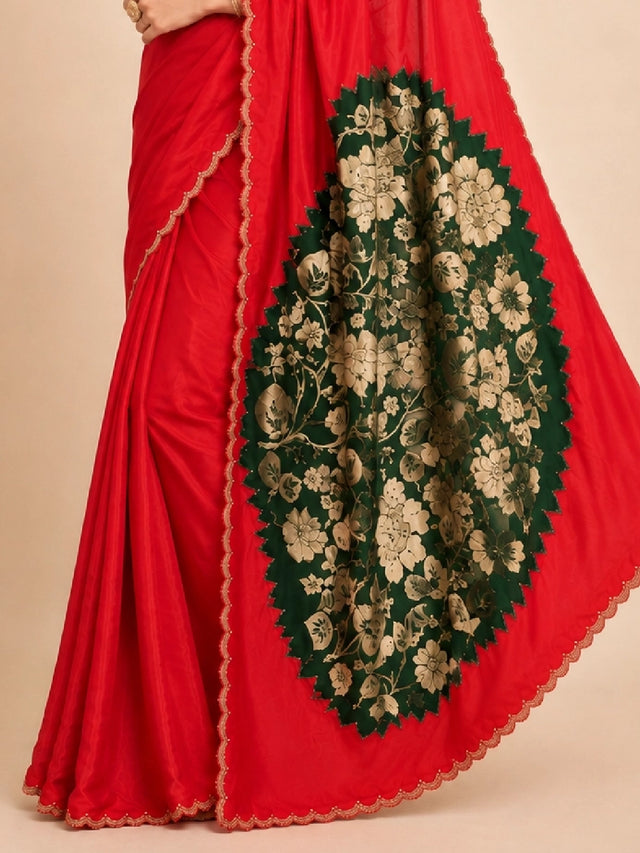Woman wearing a vibrant red saree with a gold scalloped border and traditional jewelry.