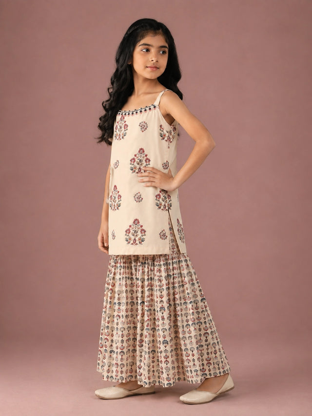 Young girl in a cream floral print strappy top and matching flared sharara set.