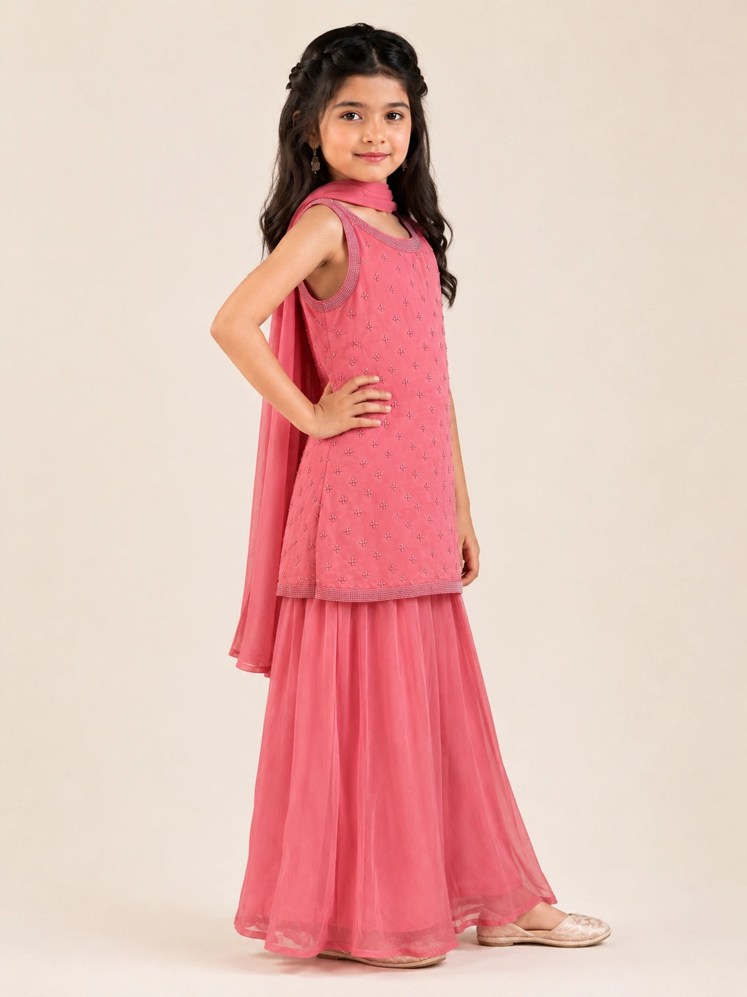 Young girl in a pink sleeveless kurta with beaded embroidery and flowy pink sharara pants.