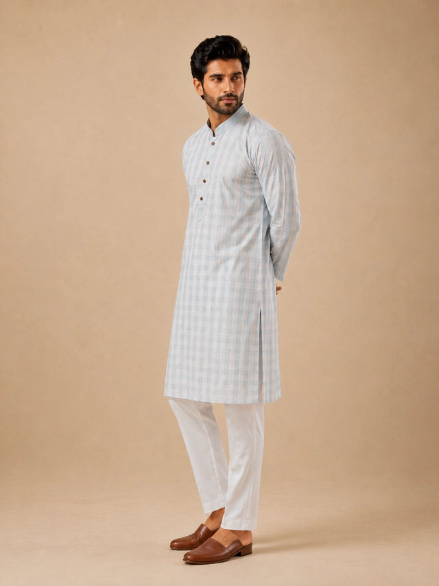 Man wearing a light sky blue and white checkered kurta with white pajamas.