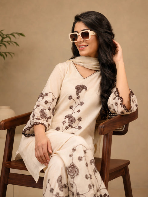 Woman wearing a cream kurta set with brown floral embroidery and a matching dupatta, styled with sunglasses.