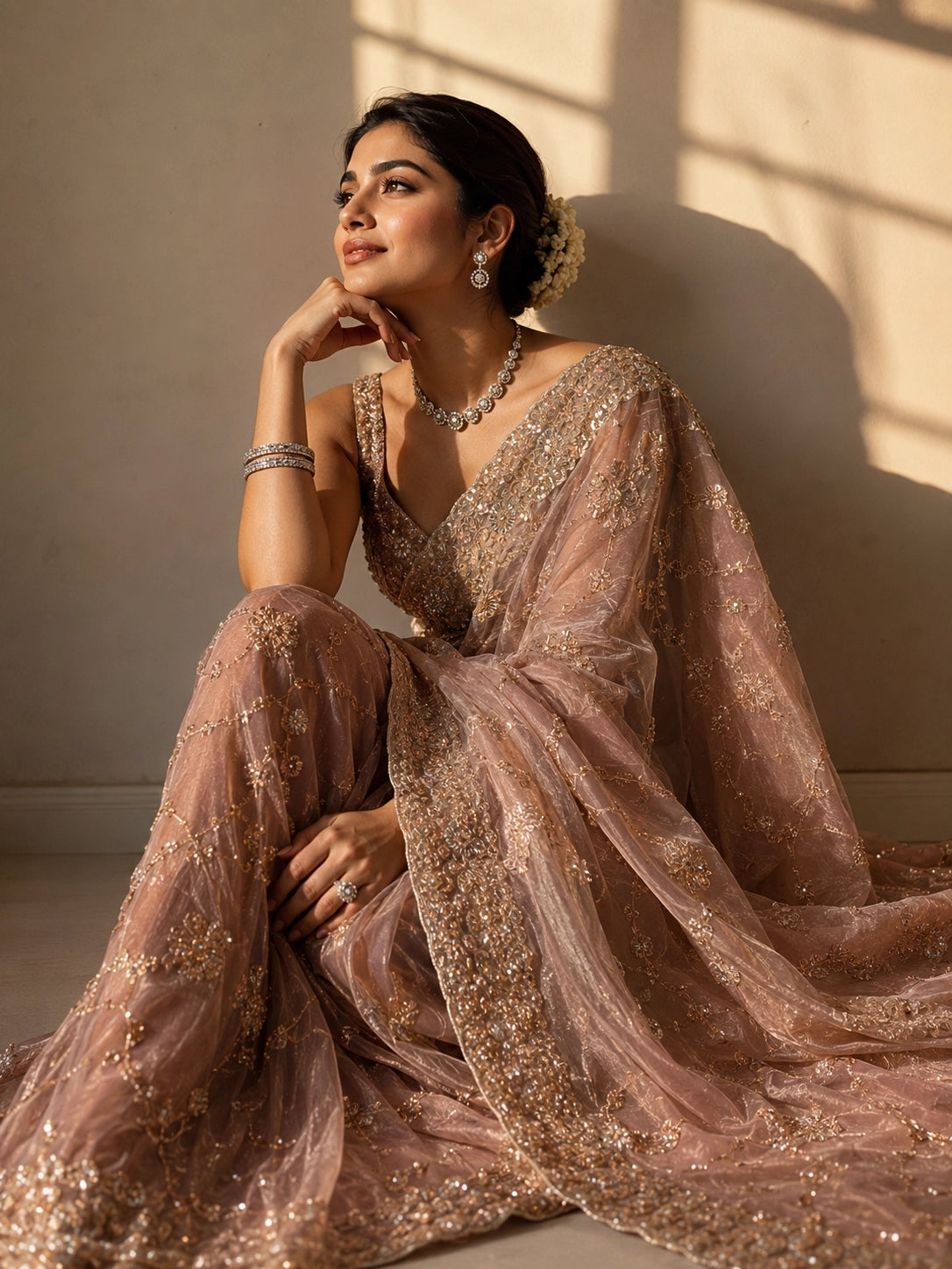 Woman in an elegant pink S3 embellished saree with intricate gold work and sleeveless blouse.