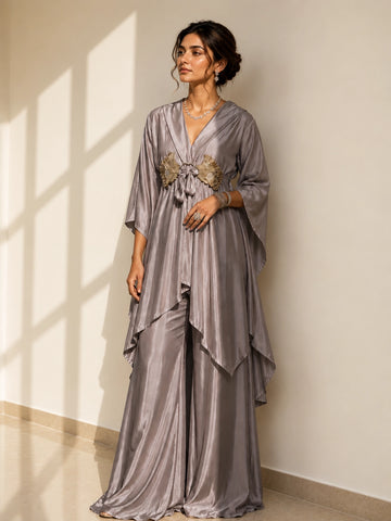 Woman in an elegant onion-colored layered kurti with golden waist detail and matching palazzo pants.