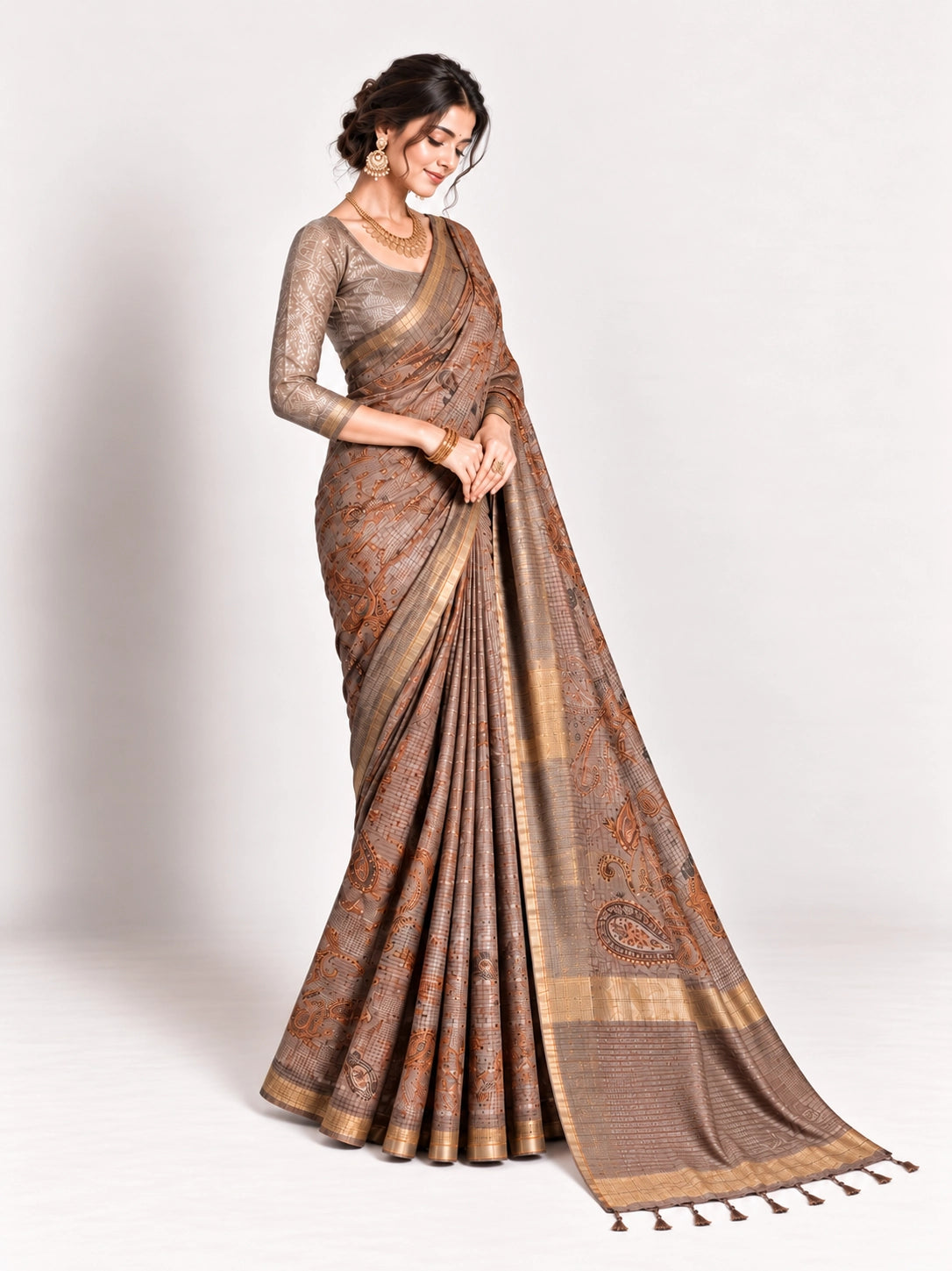 Woman in an elegant lavender grey saree with gold border and intricate paisley patterns.
