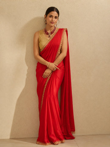 Woman in vibrant red saree with golden embroidered border and matching golden blouse.