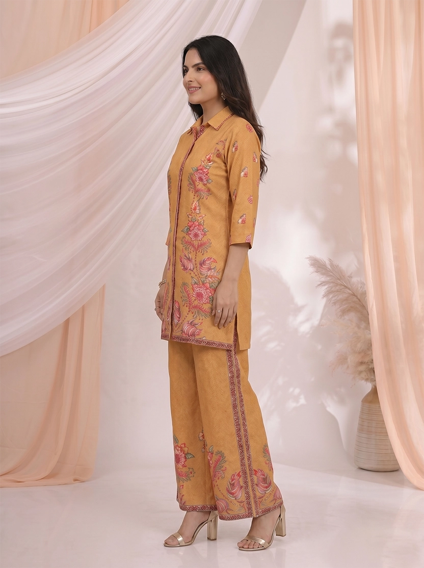 Woman wearing an ochre yellow kurta and palazzo set with a vibrant floral print.