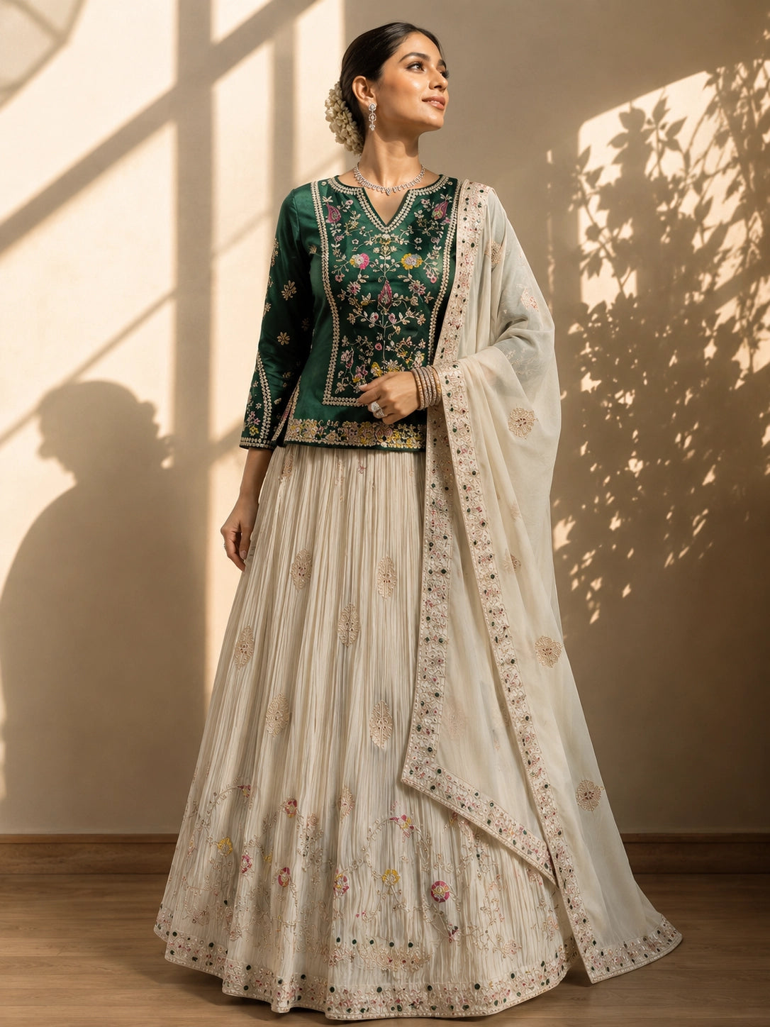Elegant woman in a dark green embroidered kurta, cream pleated skirt, and matching dupatta.