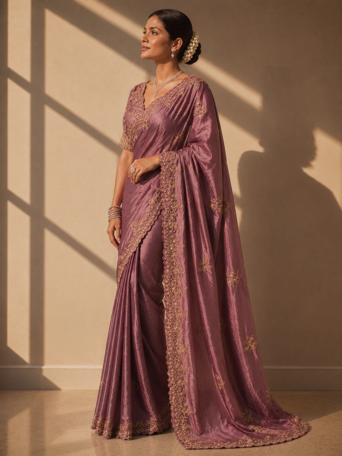 Woman in an elegant onion silk saree with intricate gold embroidery.