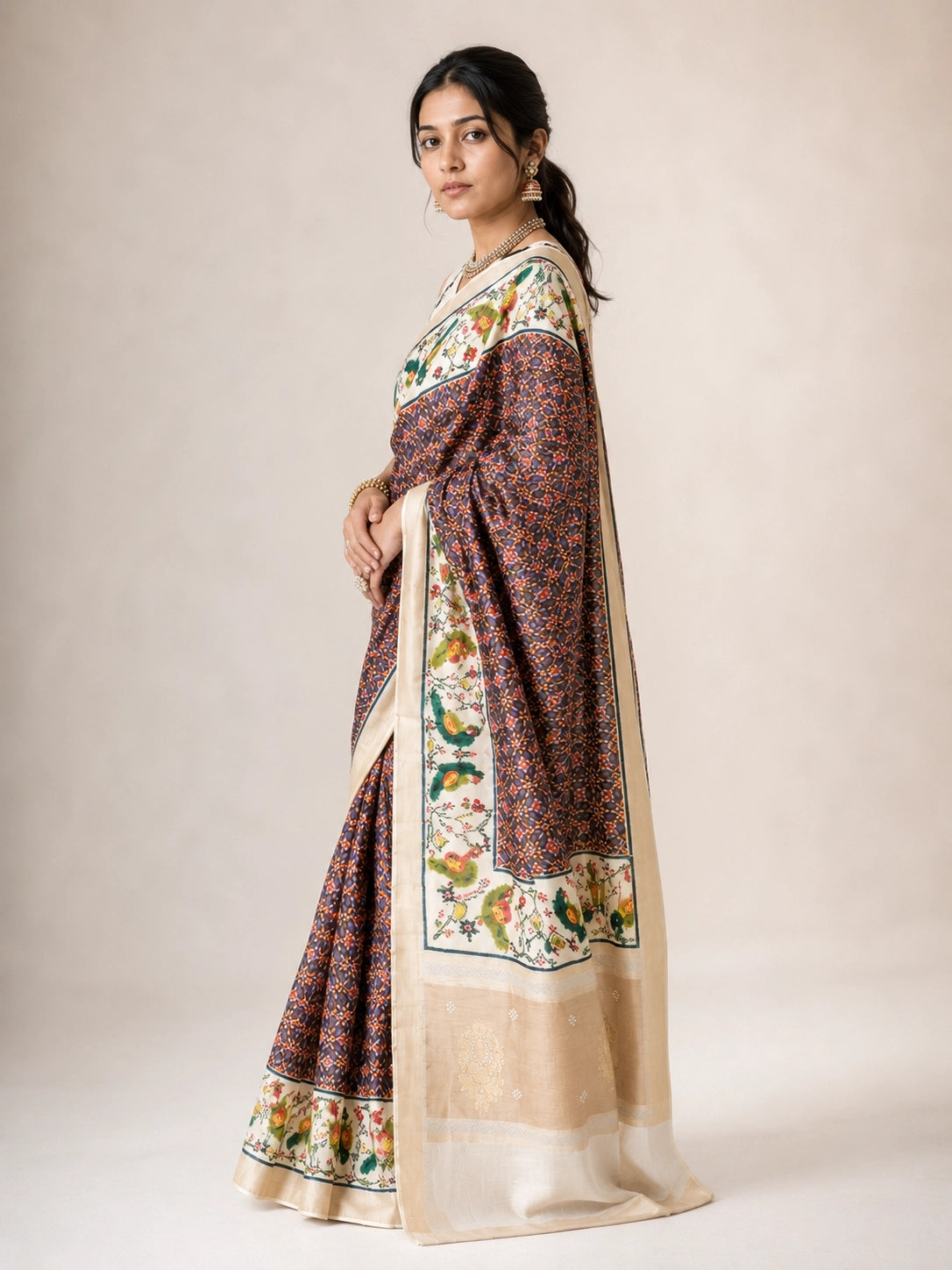 Woman in a purple  saree with intricate bird and floral patterns on pallu.