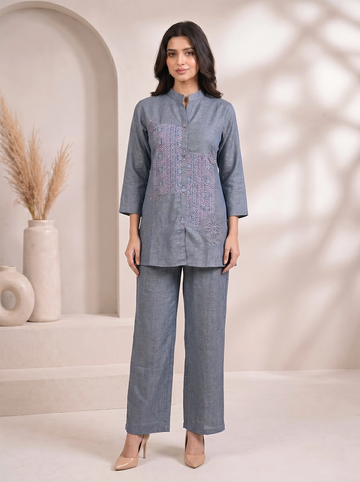 Woman wearing a blue cotton co-ord set with embroidered details on the top and straight-leg pants.