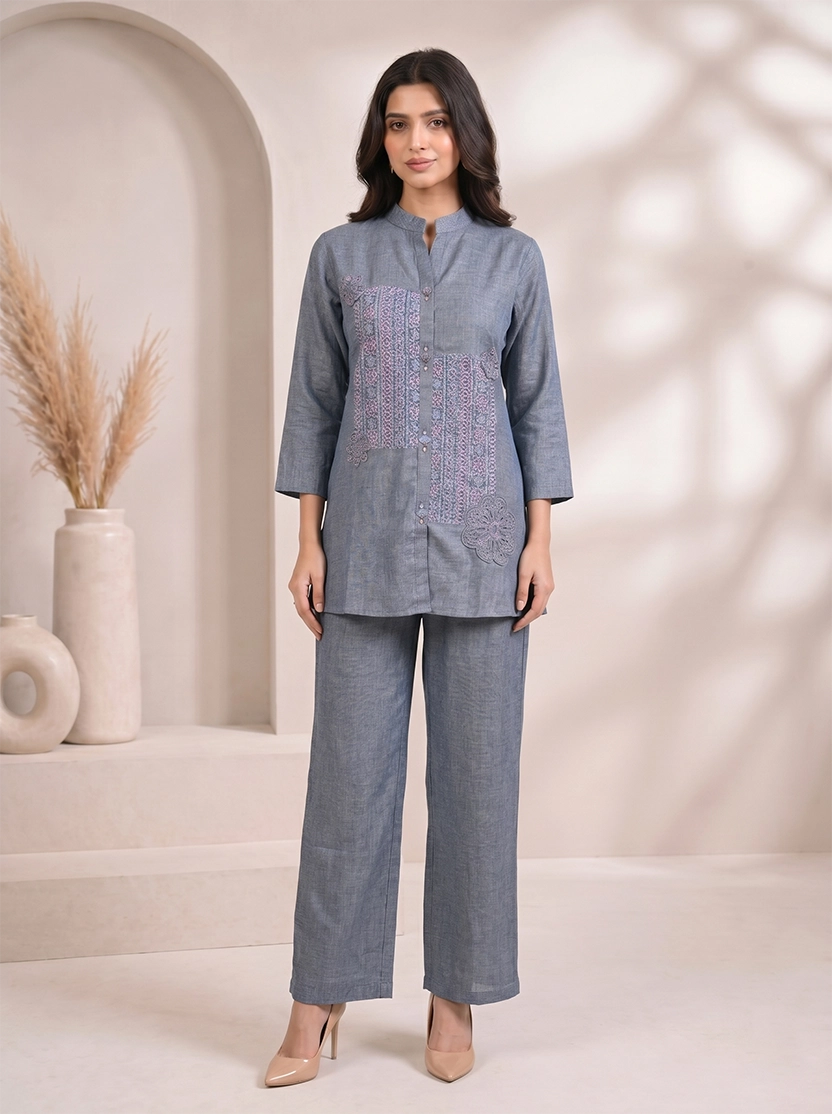 Woman wearing a blue cotton co-ord set with embroidered details on the top and straight-leg pants.