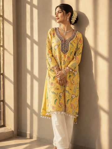 Woman wearing a vibrant yellow floral kurti with intricate embroidered V-neck and tassels.