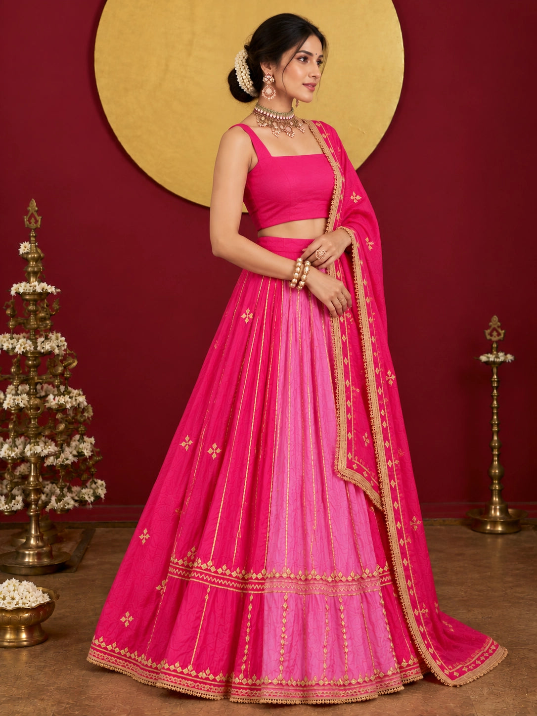 Woman in a vibrant rani pink ombre lehenga choli with gold embroidery.