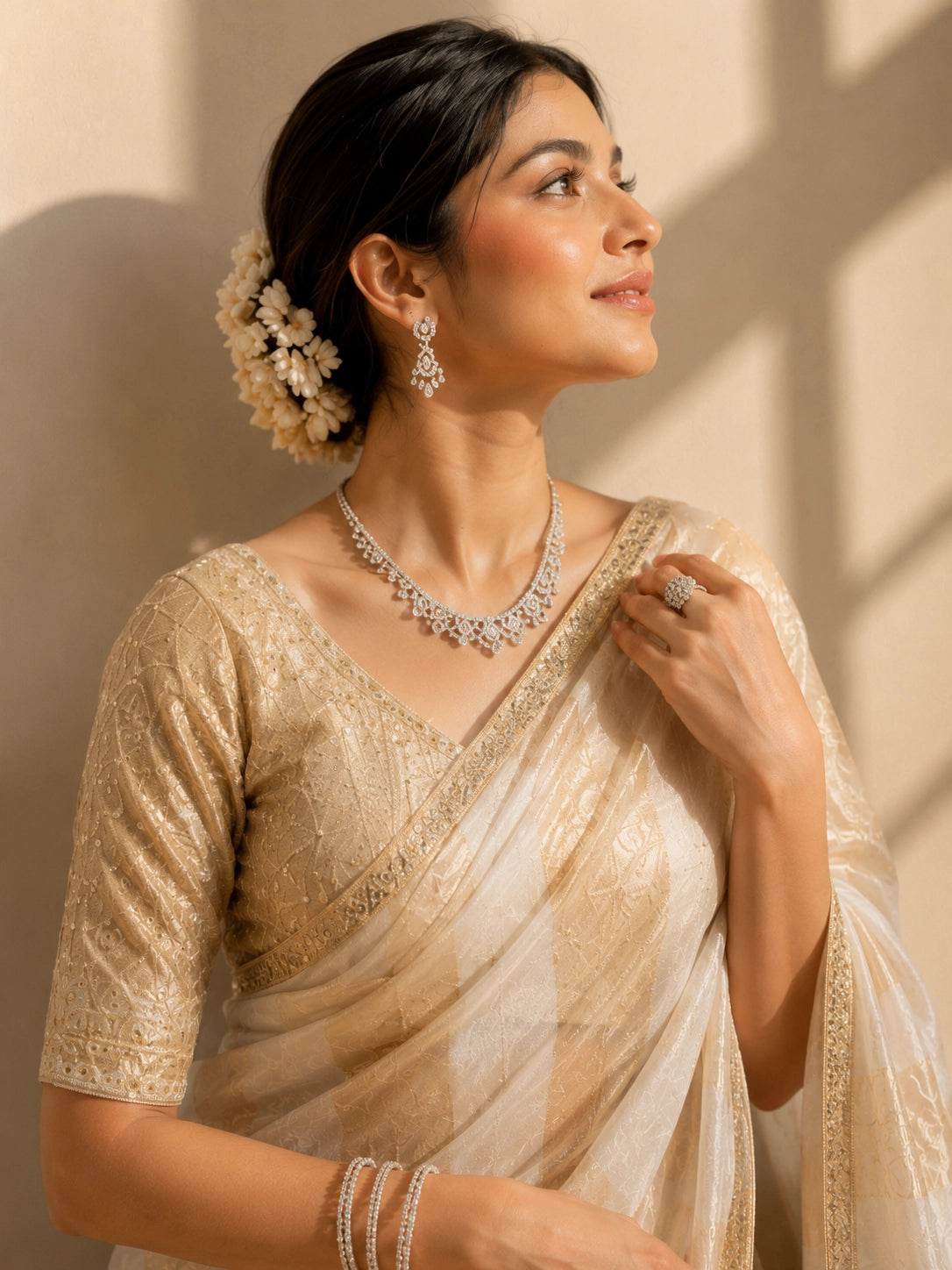 Woman in a cream and gold striped saree with an embroidered blouse.
