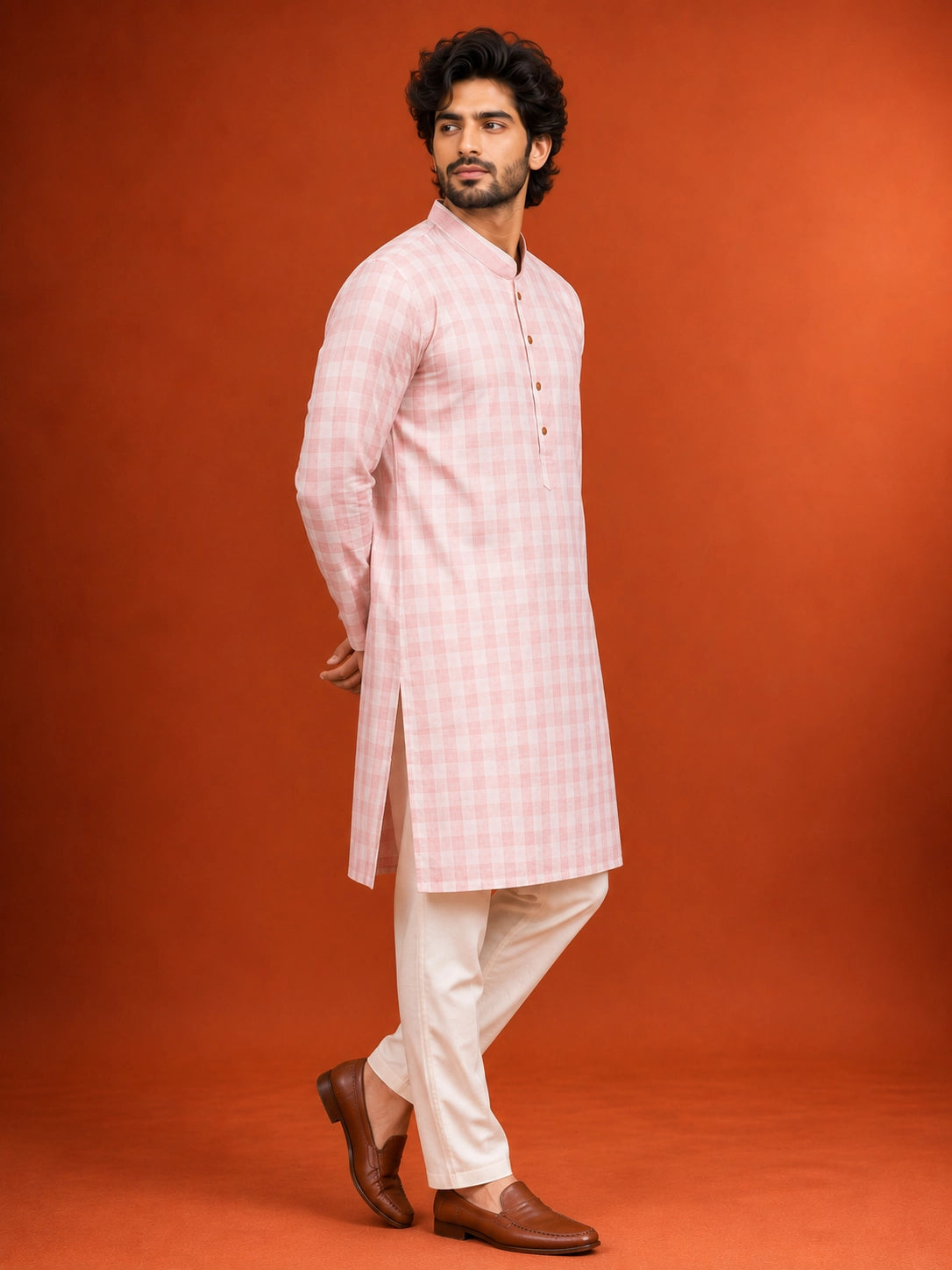 Man wearing a light pink checked kurta with a band collar and white pajama.