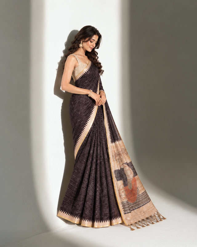 A woman in an elegant charcoal printed saree with an art-inspired beige pallu.