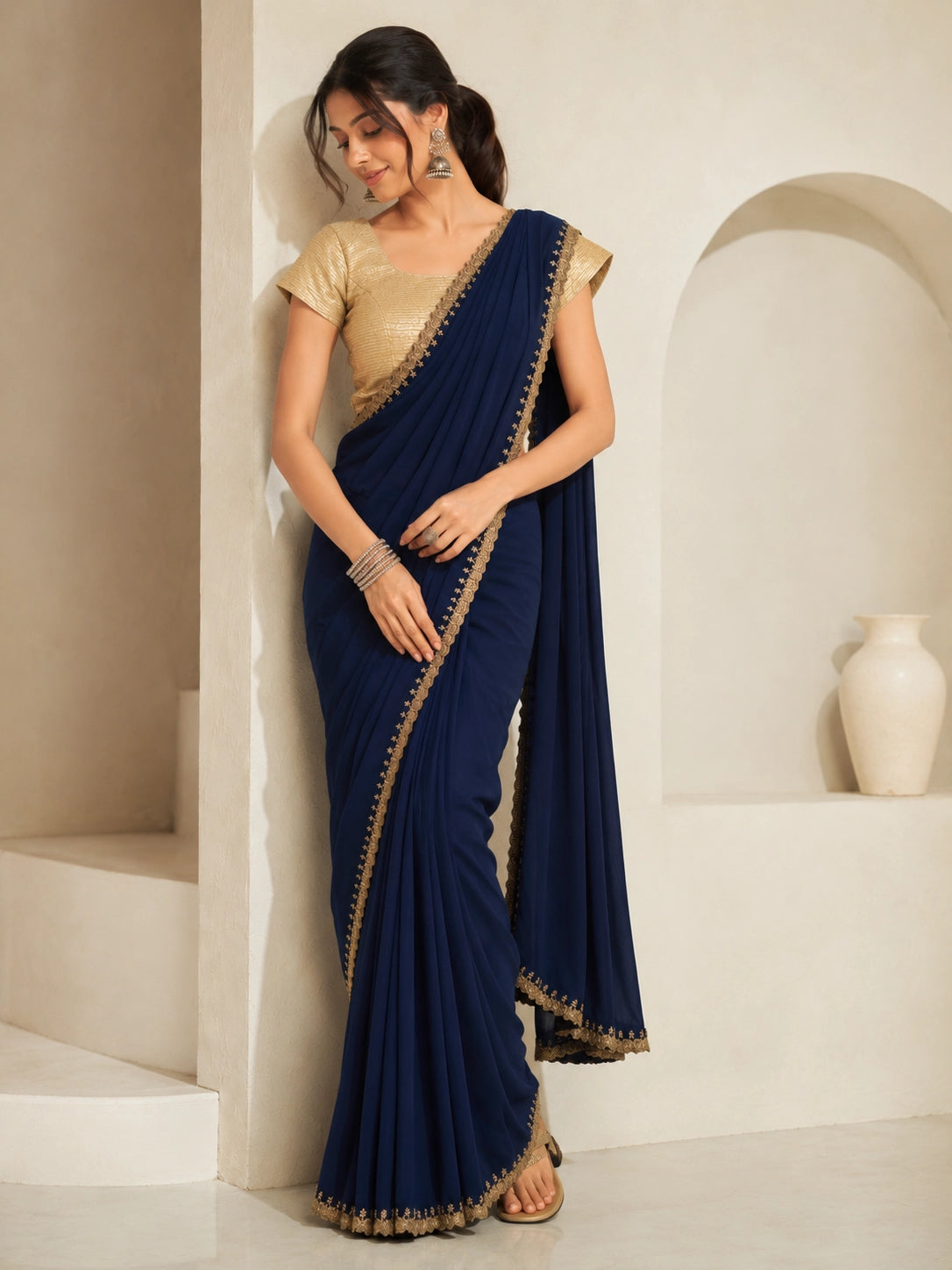 Woman wearing a navy blue saree with gold embroidered borders and a gold blouse.
