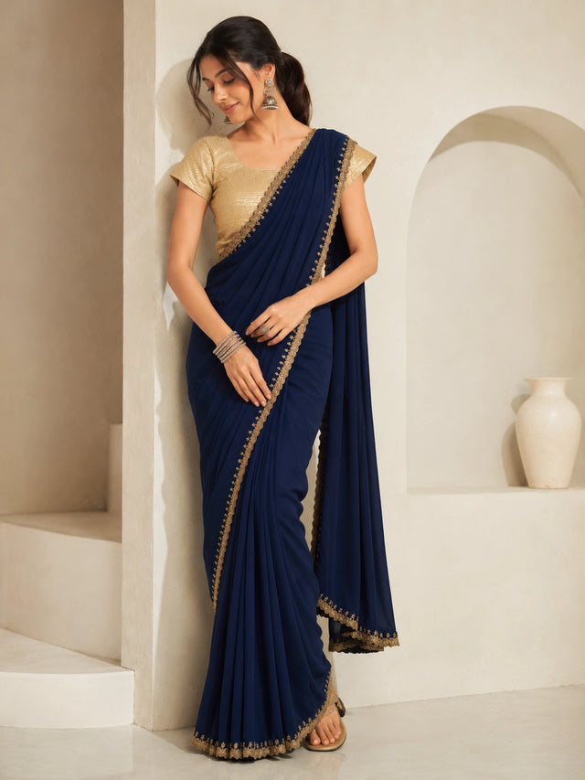 Woman wearing a navy blue saree with gold embroidered borders and a gold blouse.