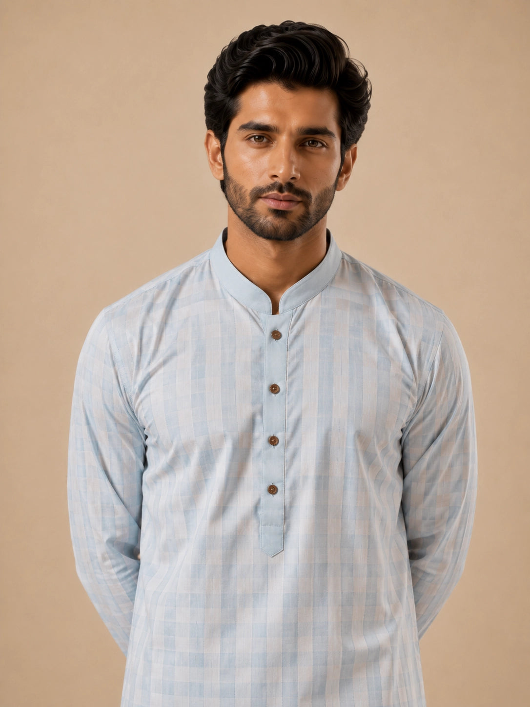 Man wearing a light sky blue and white checkered kurta with white pajamas.