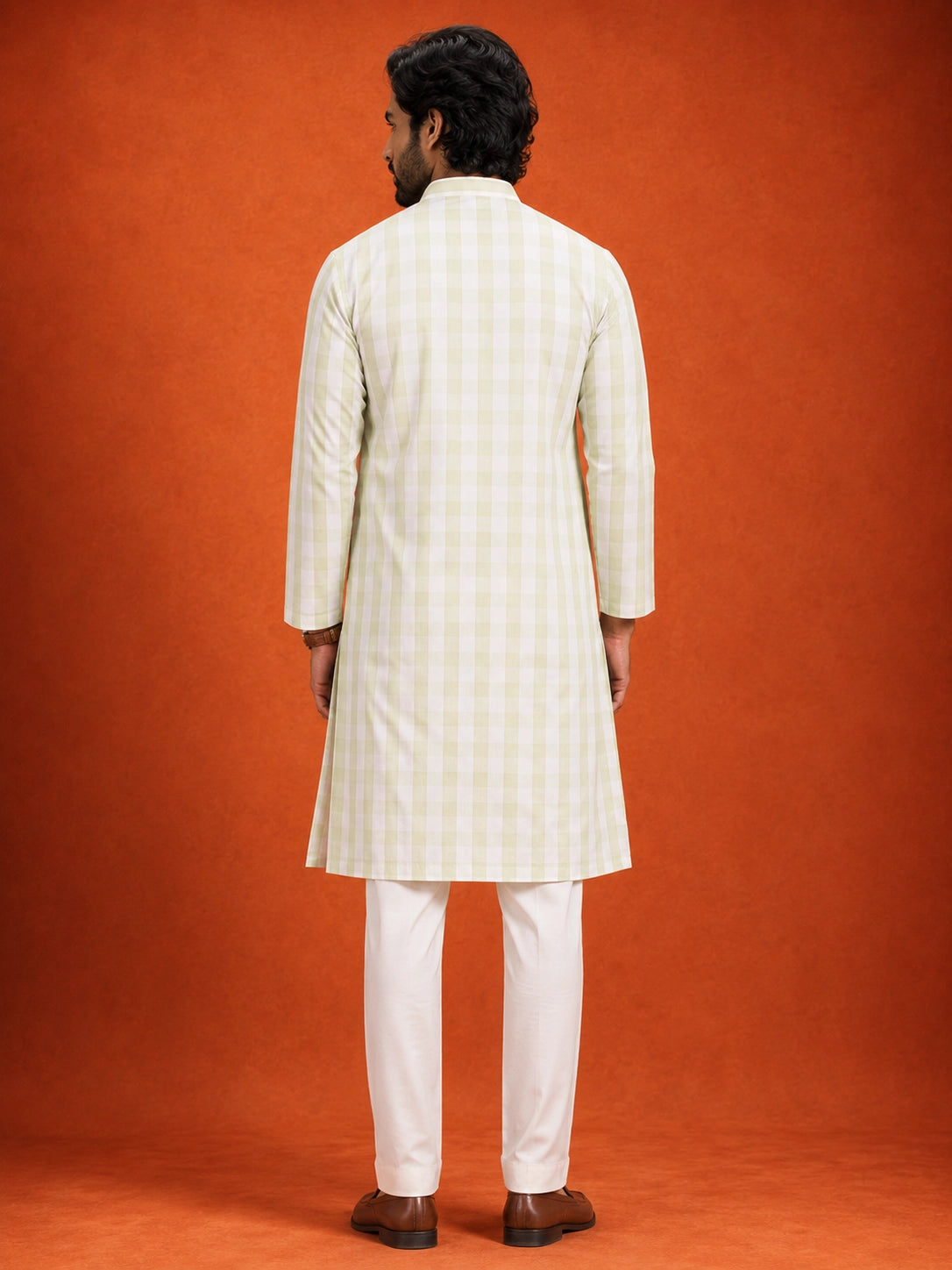 Full-length view of a man in a pista green checkered kurta and white pajama.