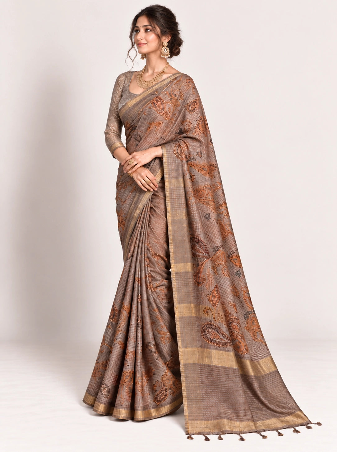 Woman in an elegant lavender grey saree with gold border and intricate paisley patterns.
