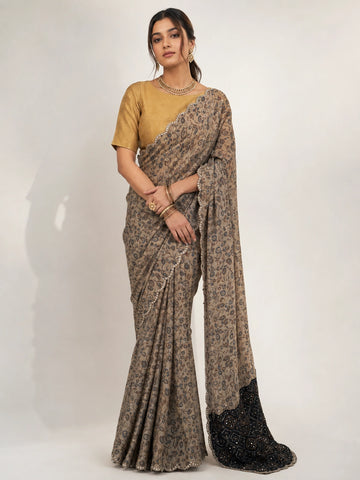 Woman wearing an elegant cream  printed saree with a gold blouse and embellished black pallu.