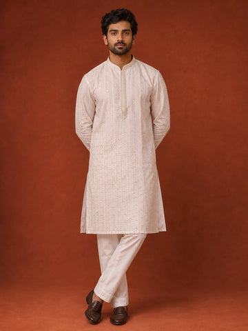 Man in elegant white kurta pajama with subtle vertical and diamond patterns.