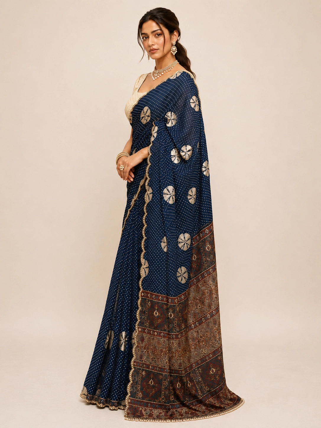 Woman in navy blue bandhani saree with cream blouse and gold jewelry.